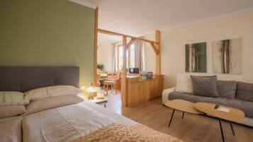 Un dormitorio con cama, sofá, una mesita y una zona de kitchenette.