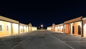 A row of motel rooms with a central walkway, each room has a door and a small window, and the exterior is lit by exterior lights. - Autohotel Venezia (Mirano)