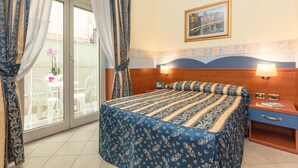A hotel room with a bed, two bedside tables, a window with curtains, a picture on the wall, and a view of the outside. - Borgo del Mare (Civitavecchia)
