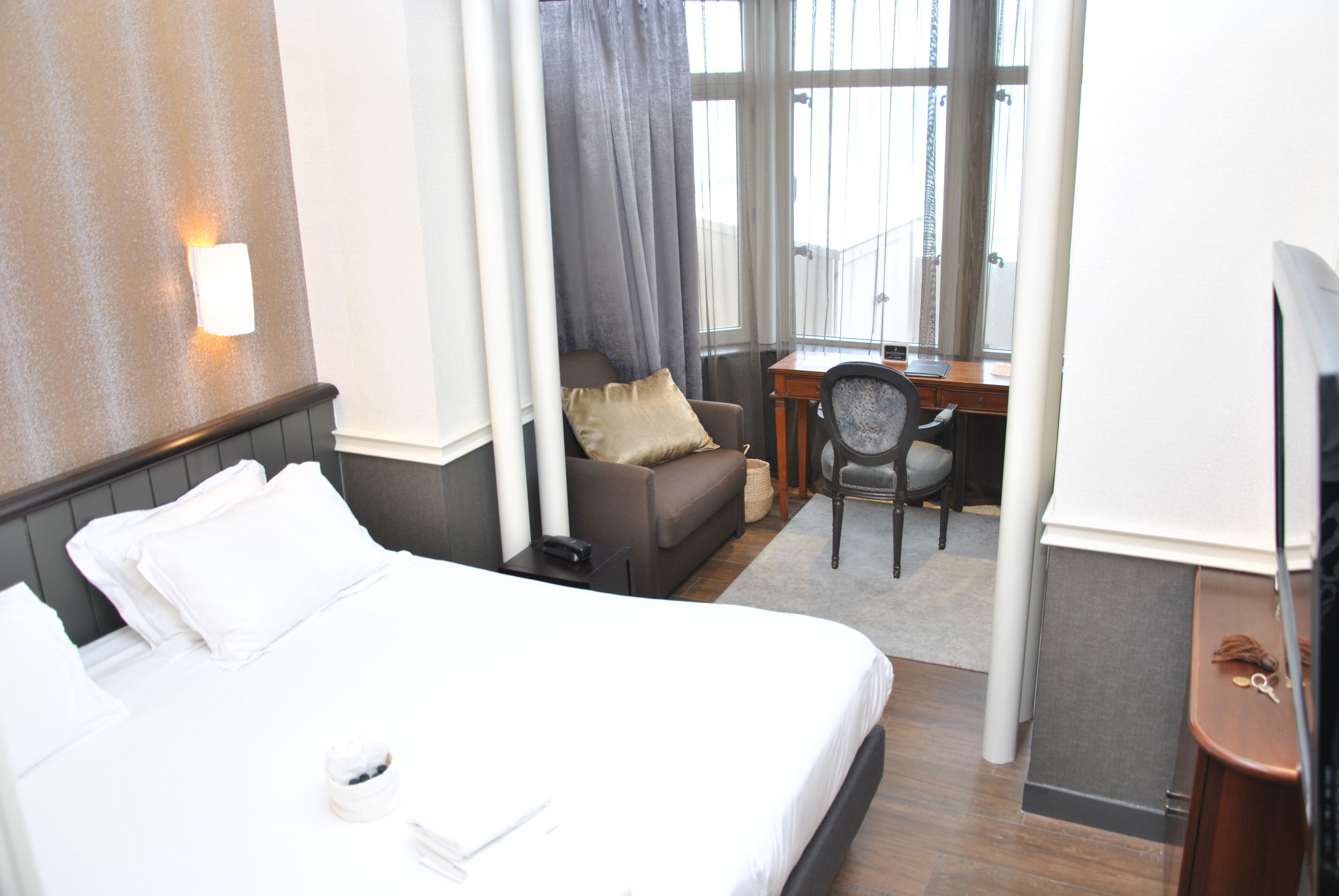 Une chambre d’hôtel avec un grand lit, un bureau, une chaise et un téléviseur.