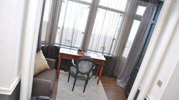 A small, well-lit room with a wooden desk, a cushioned chair, and a sofa.