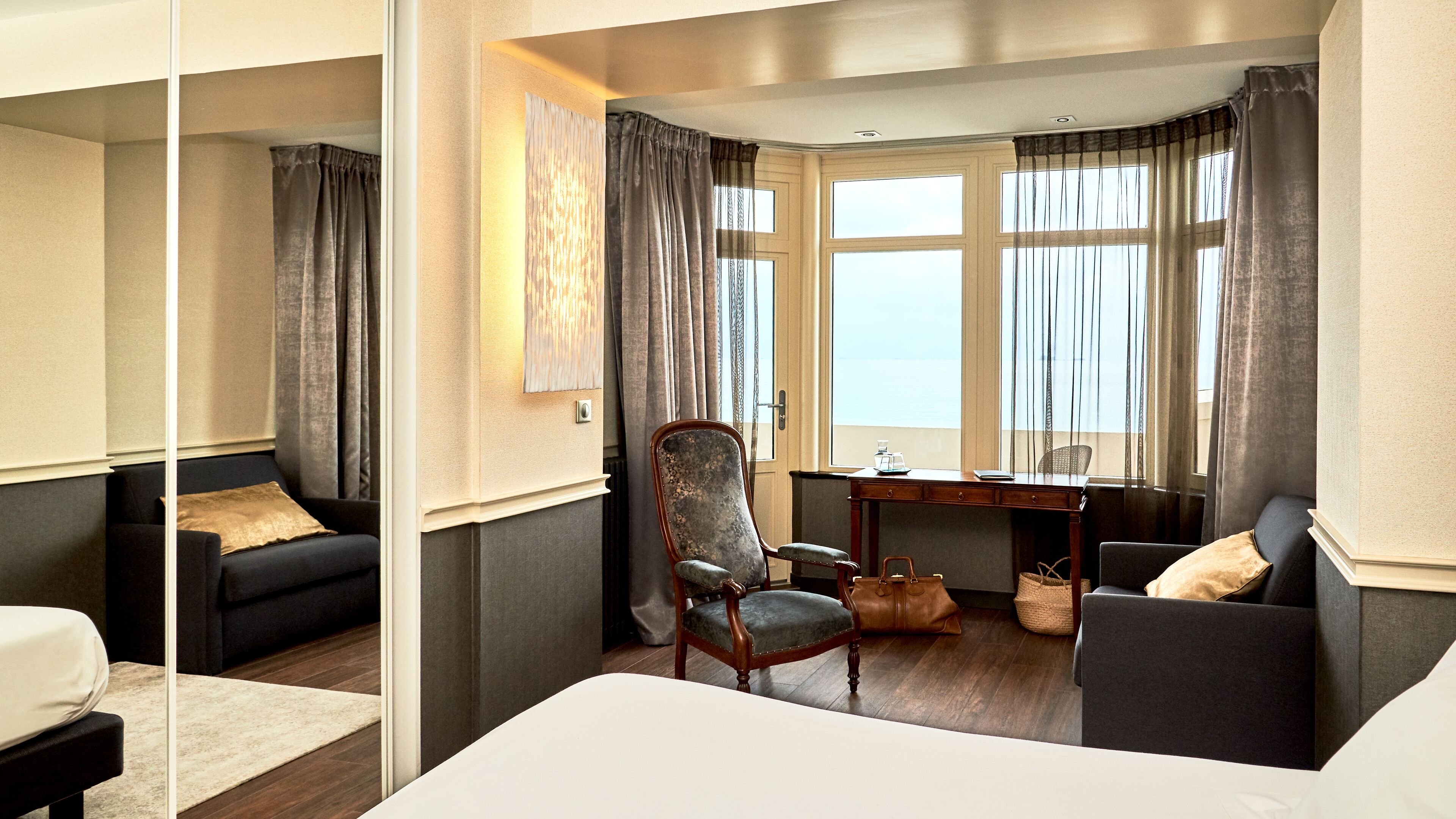 Een hotelkamer met een bed, twee banken, een bureau en een stoel.
