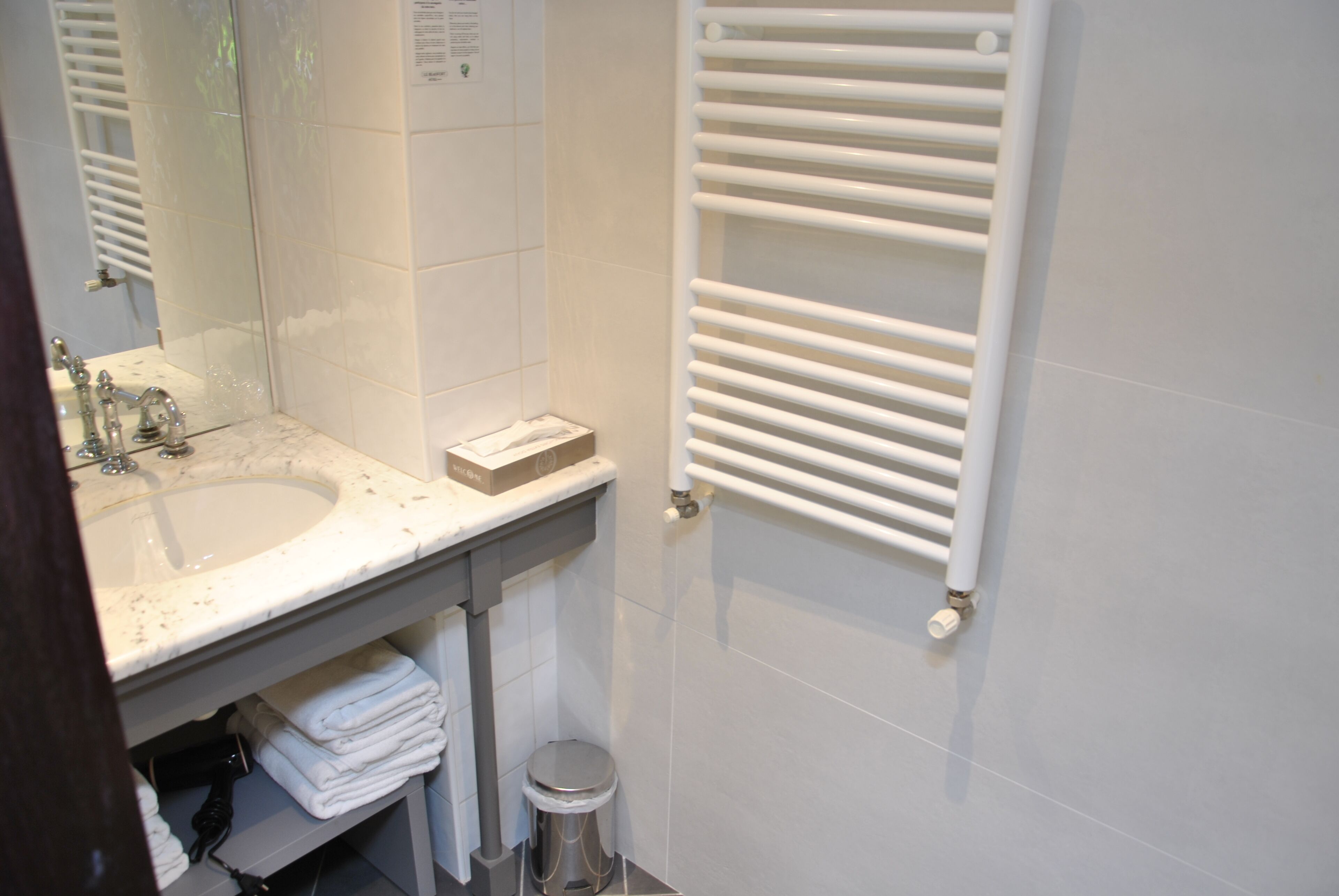 Ein Badezimmer mit Waschbecken, Spiegel, Handtuchhalter und Toilette.