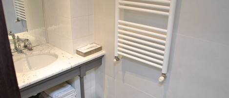 Ein Badezimmer mit Waschbecken, Spiegel, Handtuchhalter und Toilette.