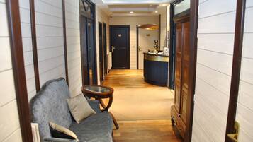 A hallway with a sofa, a small table, and a door leading to a room.