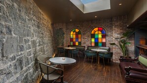 A cozy interior with a stone wall, wooden flooring, and a skylight above a seating area with tables and chairs. - Victoria Hotel (Galway)