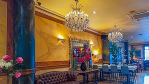A lobby with a leather sofa, a coffee table, a chandelier, and a mirror. - Victoria Hotel (Galway)