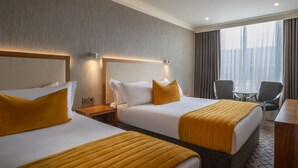 A hotel room with two beds, a desk, and a chair. - Victoria Hotel (Galway)