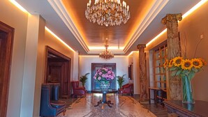A grand hallway with a marble floor, a large chandelier, and a floral arrangement. - Victoria Hotel (Galway)