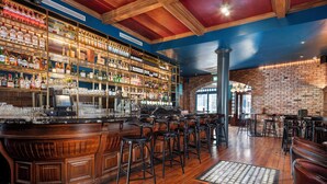 A bar with wooden floors, a brick wall, and a variety of bottles and glasses on shelves. - Eyre Square Hotel (Galway)