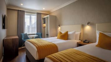 A hotel room with two beds, a desk, a chair, and a window with curtains.
