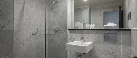 Un baño moderno con ducha envuelta en vidrio, un lavamanos blanco y un inodoro.