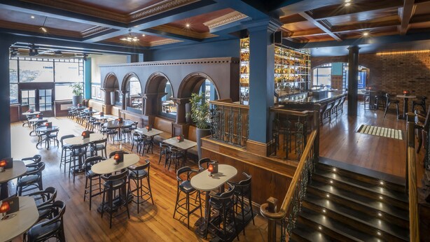 A spacious restaurant with high ceilings, exposed beams, and a variety of seating options including tables and bar stools. - Eyre Square Hotel (Galway)