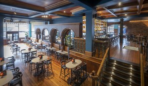 A spacious restaurant with high ceilings, exposed beams, and a variety of seating options including tables and bar stools. - Eyre Square Hotel (Galway)