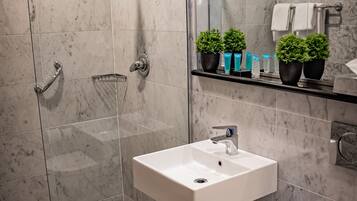 Un baño moderno con ducha de vidrio, lavamanos blanco y retrete.
