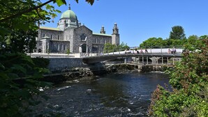 A historic stone building with a green dome and a bridge over a river. - Eyre Square Hotel (Galway)
