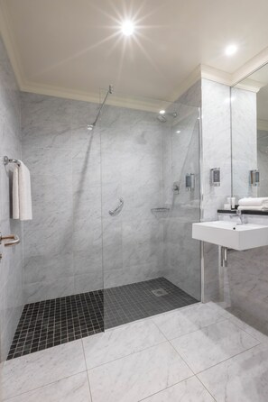 Enjoy a refreshing shower in the bathroom, featuring a glass-enclosed shower, sink, and large mirror.