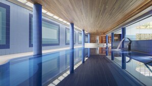 Una piscina interior moderna con paredes de azulejos azules y techo de madera.