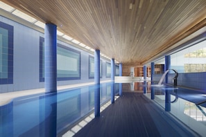 Relax by the sleek pool surrounded by blue-tiled walls and columns in a clean, structured environment.