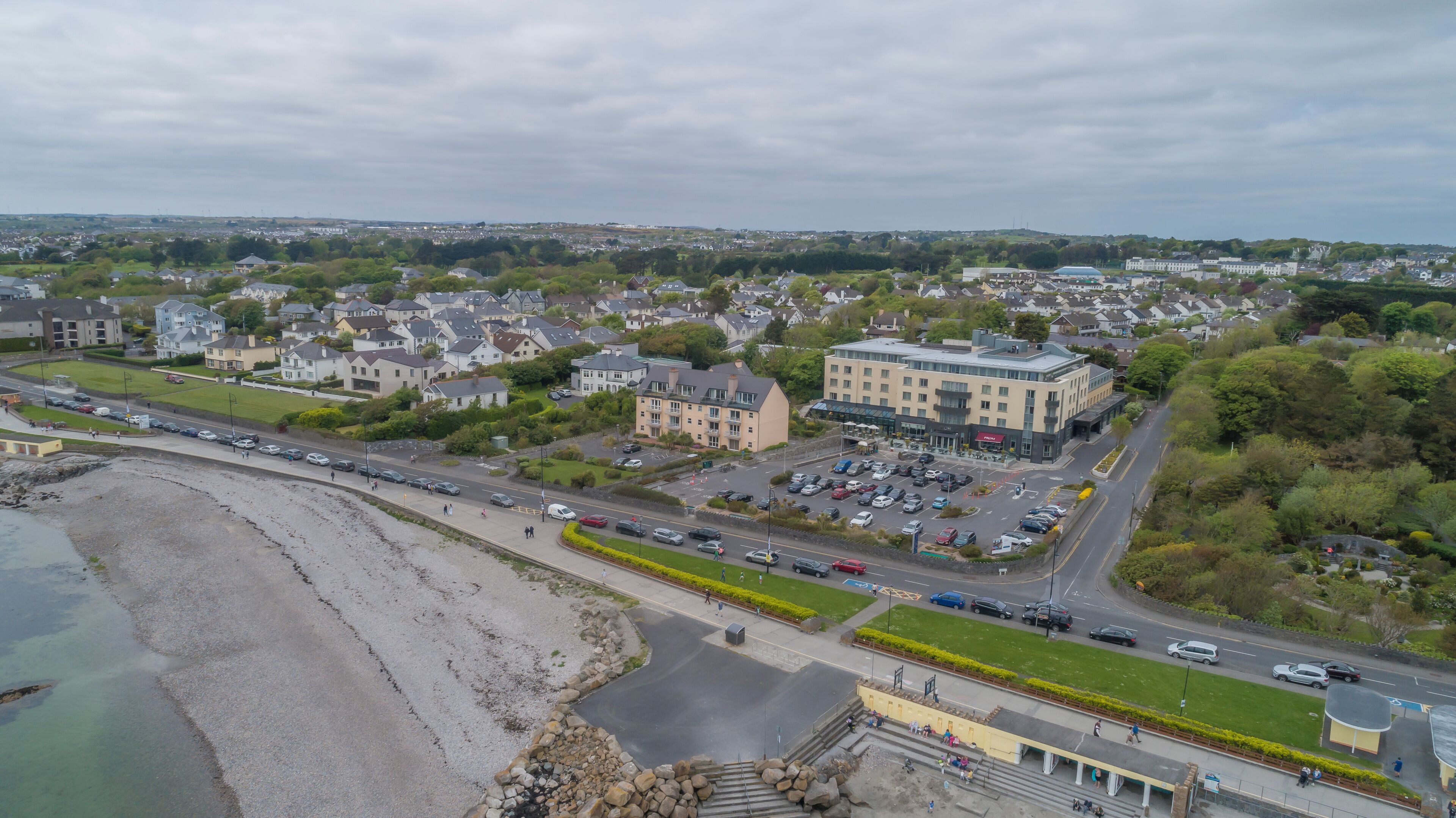 A coastal town with a prominent hotel featuring a large parking lot and a central building with a flat roof.