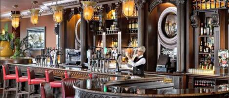 Un bar amb caires vermelles, un barman i una àmplia selecció de begudes al bar.