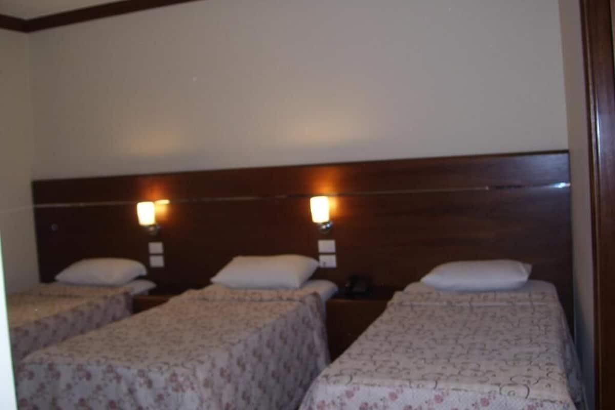 Ein Hotelzimmer mit zwei Einzelbetten, jeweils mit Kopfteil und Nachttischlampen.