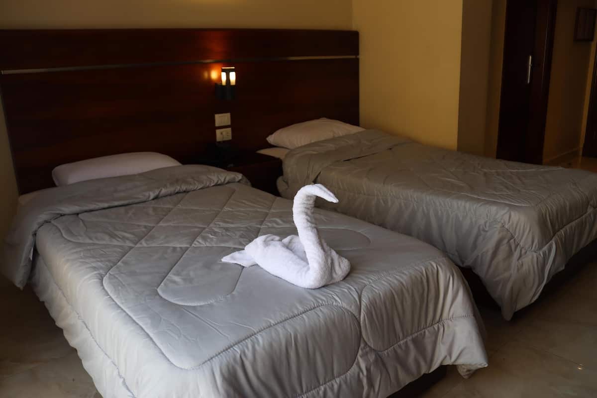 Ein Hotelzimmer mit zwei Betten, jeweils mit Kopfstütze und Nachttisch.