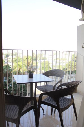 Varanda com mesa e cadeiras, oferecendo vista para uma área residencial com vegetação e edifícios.