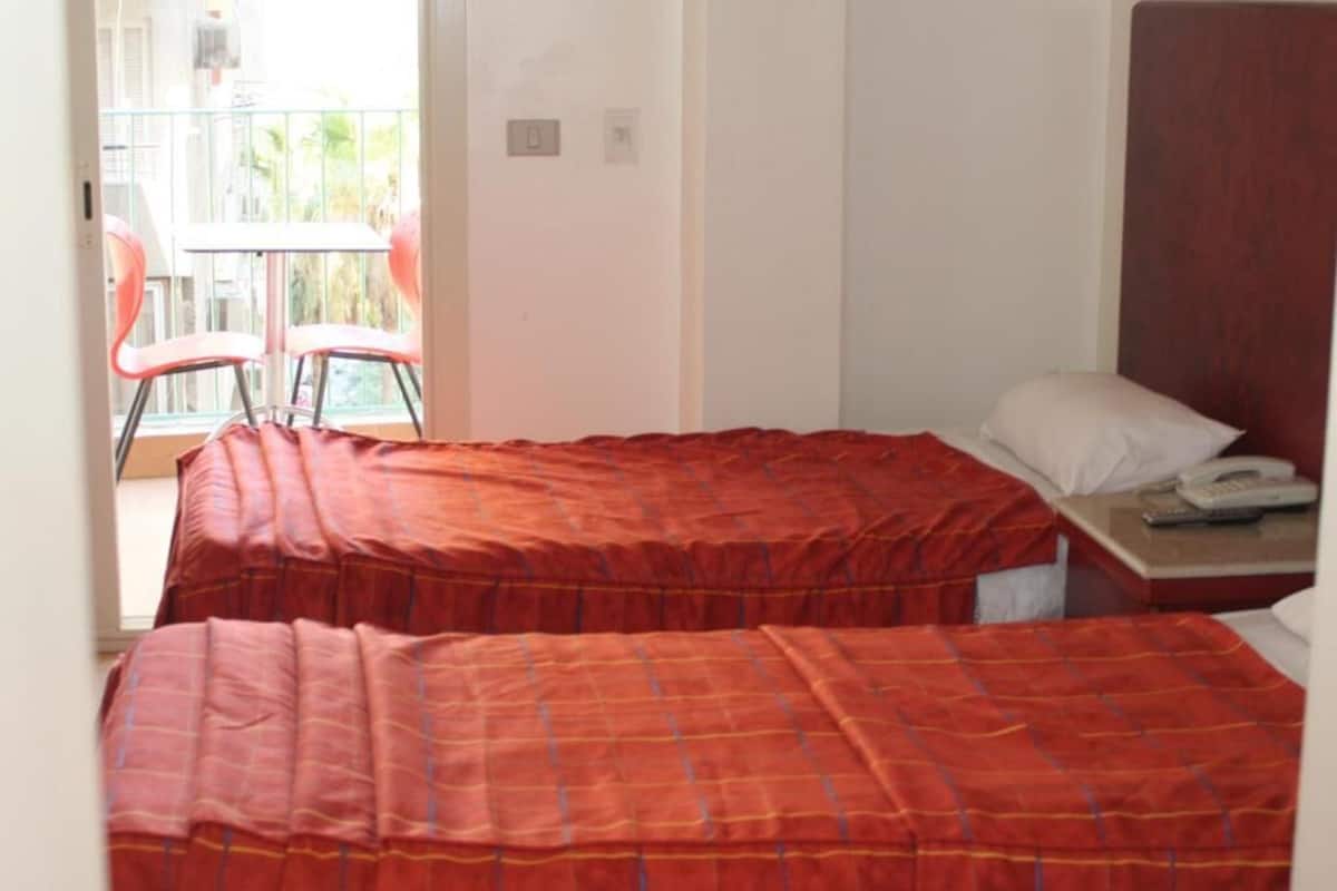 Ein Zimmer mit zwei Betten, einem kleinen Tisch und einem Stuhl.