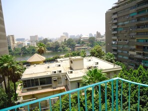 Um edifício alto com várias varandas com vista para um rio e áreas verdes.