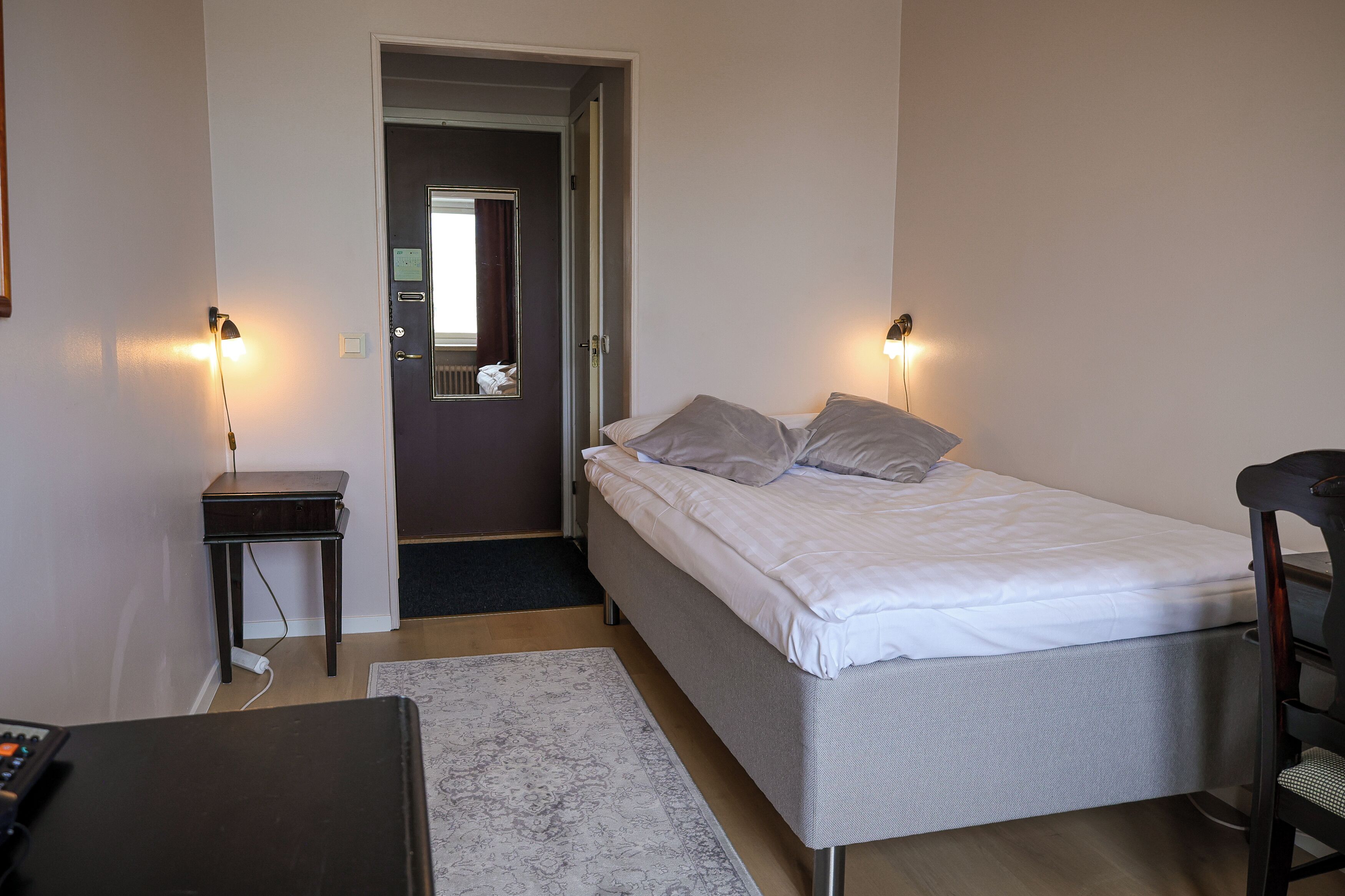 Une chambre à coucher avec un lit, des tables de chevet et un bureau.