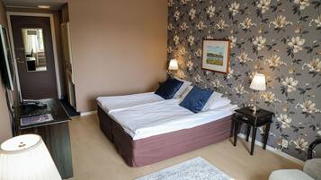 Un dormitorio con cama, mesitas de noche, escritorio y silla.