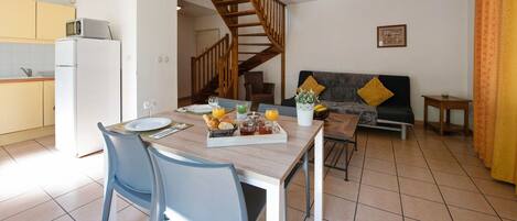 Una cocina moderna con comedor, una escalera y una sala de estar con sofá y cojines.