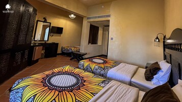 Habitación de hotel con dos camas, un escritorio, una silla, un televisor, un espejo y un adorno en la pared.