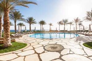 A pool area with a circular pool, lounge chairs, palm trees, and a clear sky. - Dahab Paradise (Dahab)