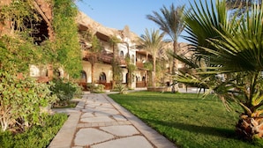 A courtyard with a stone pathway leading to a building with arched windows and a balcony. - Dahab Paradise (Dahab)