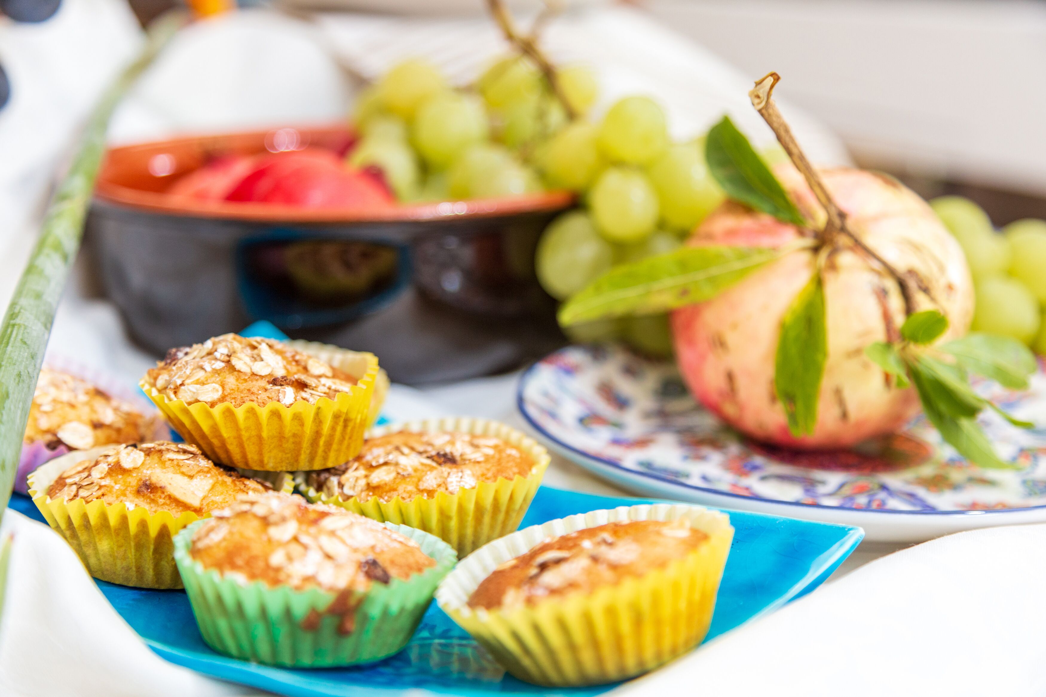 Una mesa con muffins, un tazón de sandía y un plato con uvas y un melocotón.