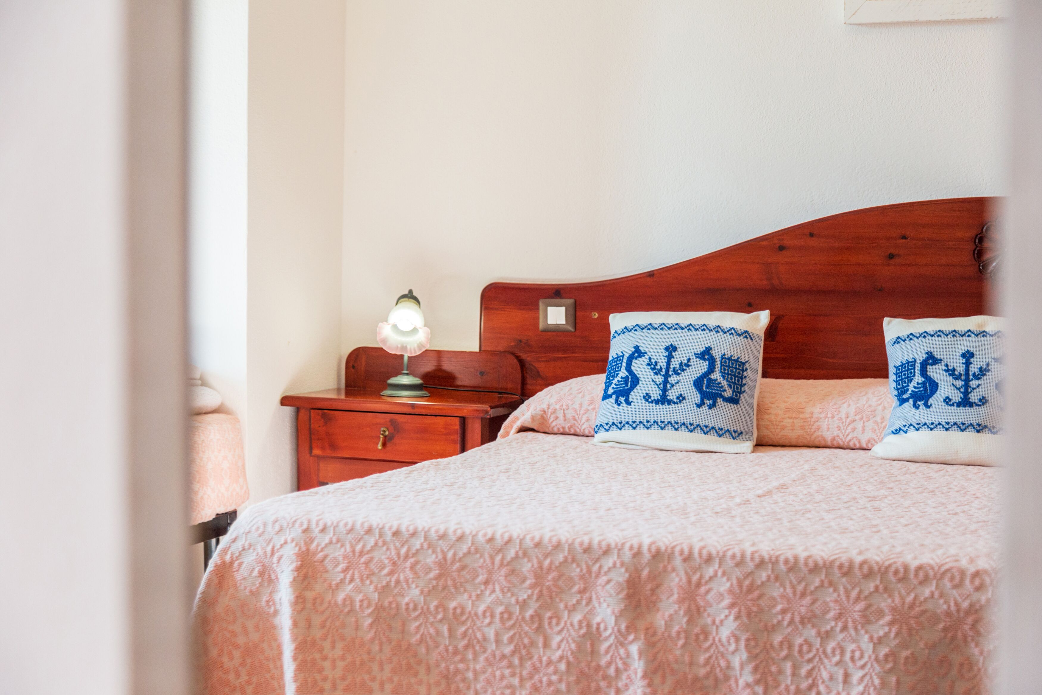 Une chambre à coucher avec une tête de lit en bois, une table de chevet avec une lampe et deux coussins décoratifs.