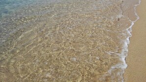 Ein Strand mit klarem, flachem Wasser und einem Sandstrand.