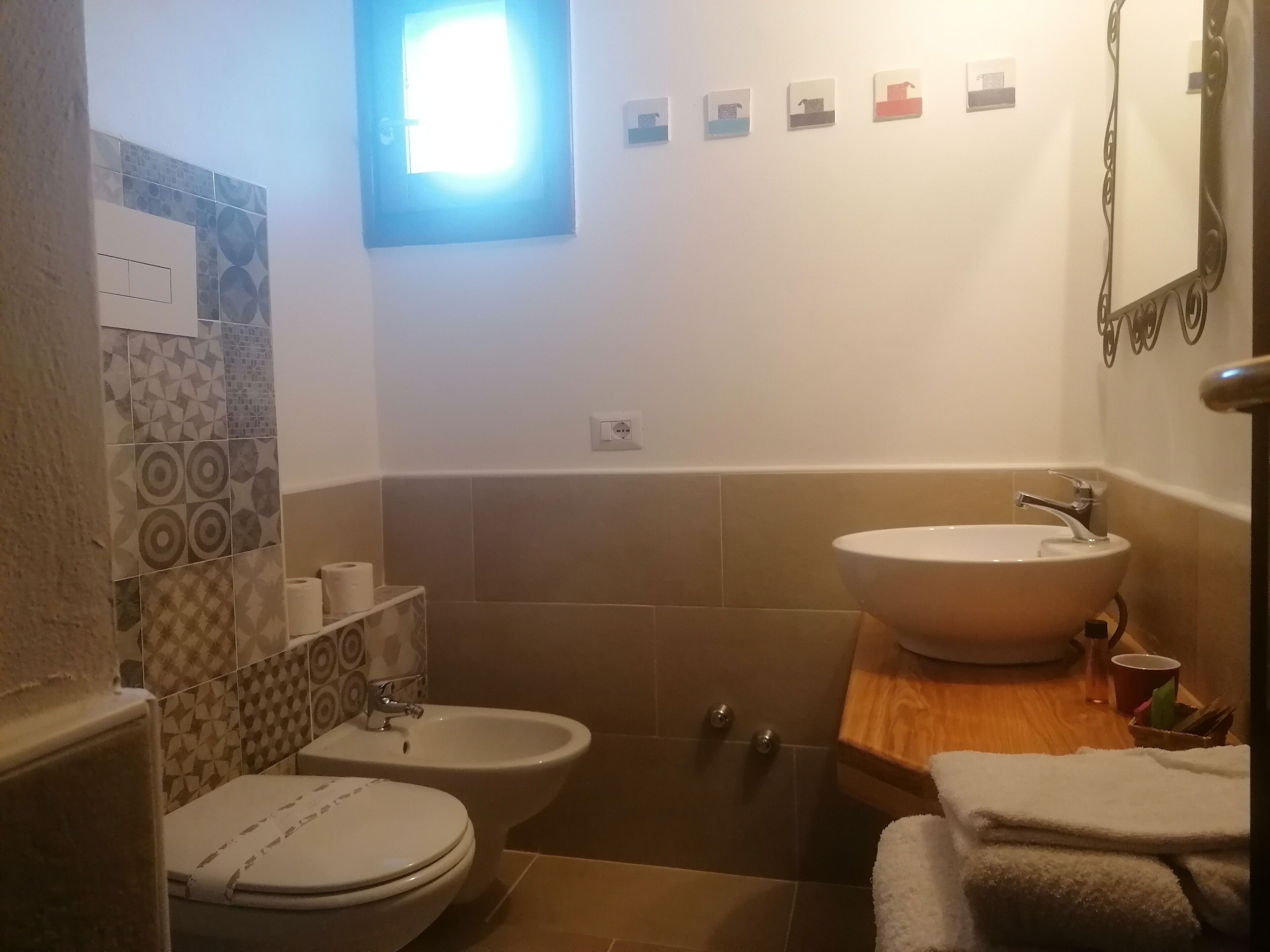 A bathroom with a toilet, bidet, and sink. There are towels on the counter.