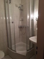 A glass-enclosed shower stall with a handheld showerhead and a handheld shower attachment.