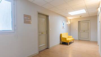 A hallway with doors labeled 201-225 and 226-229, a yellow chair, and a ceiling with fluorescent lights.