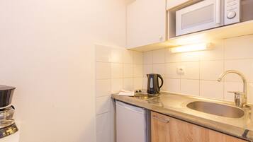 A compact kitchen with a microwave, sink, and coffee maker.