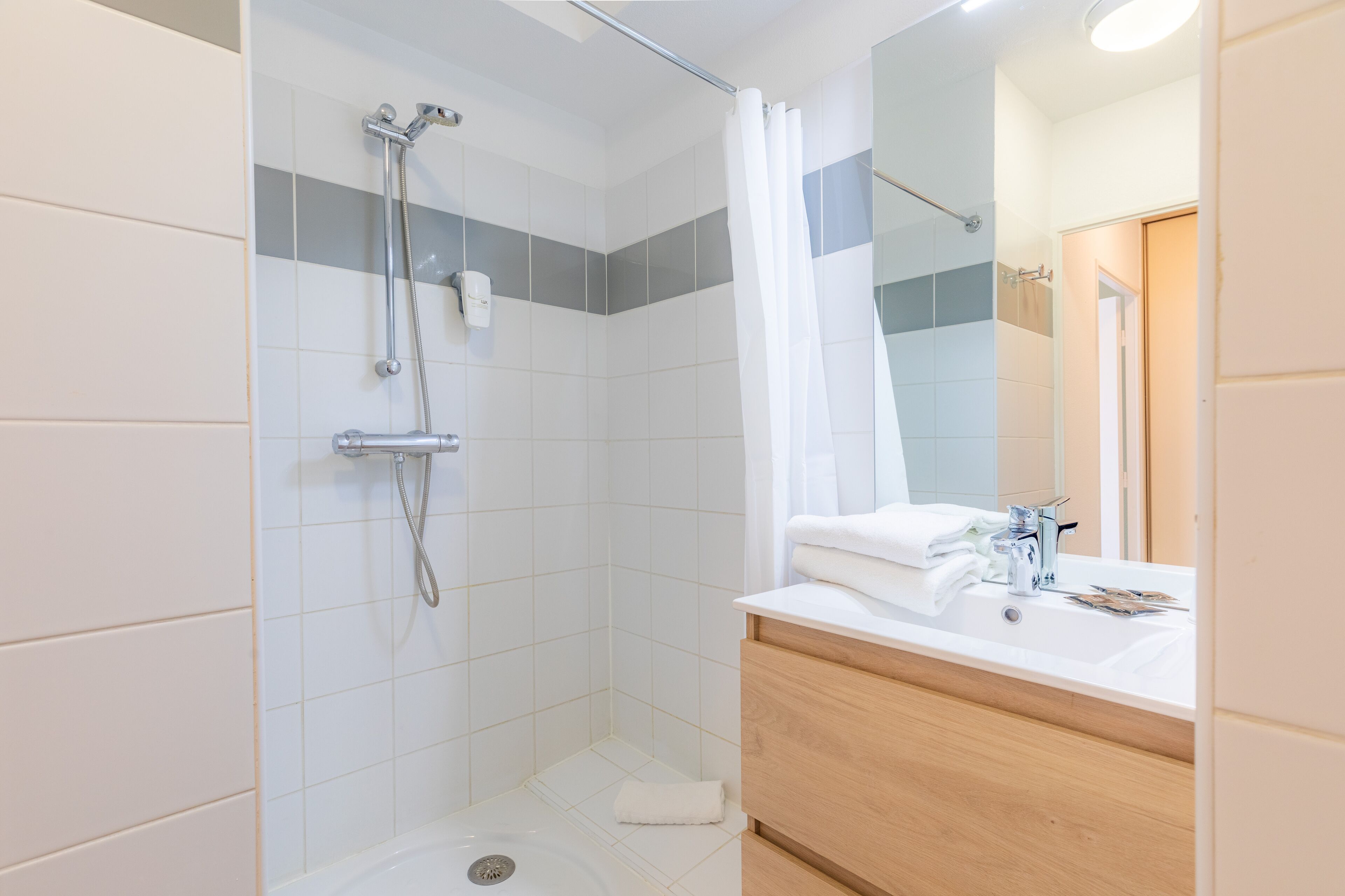 Un baño moderno con ducha, lavabo y espejo.