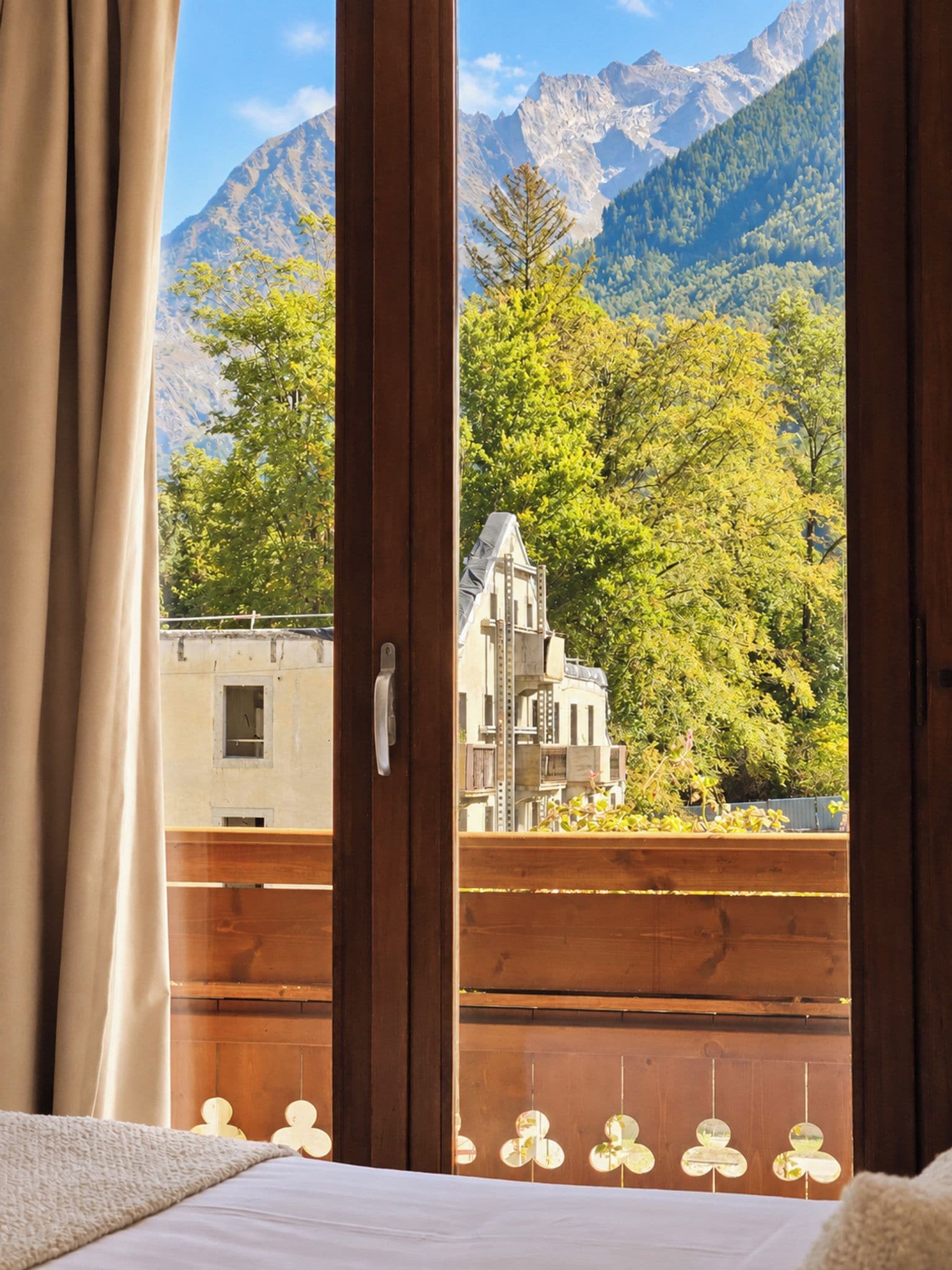Ein Zimmer mit großem Fenster und Blick auf eine Berglandschaft sowie ein Gebäude mit markanter Architektur.