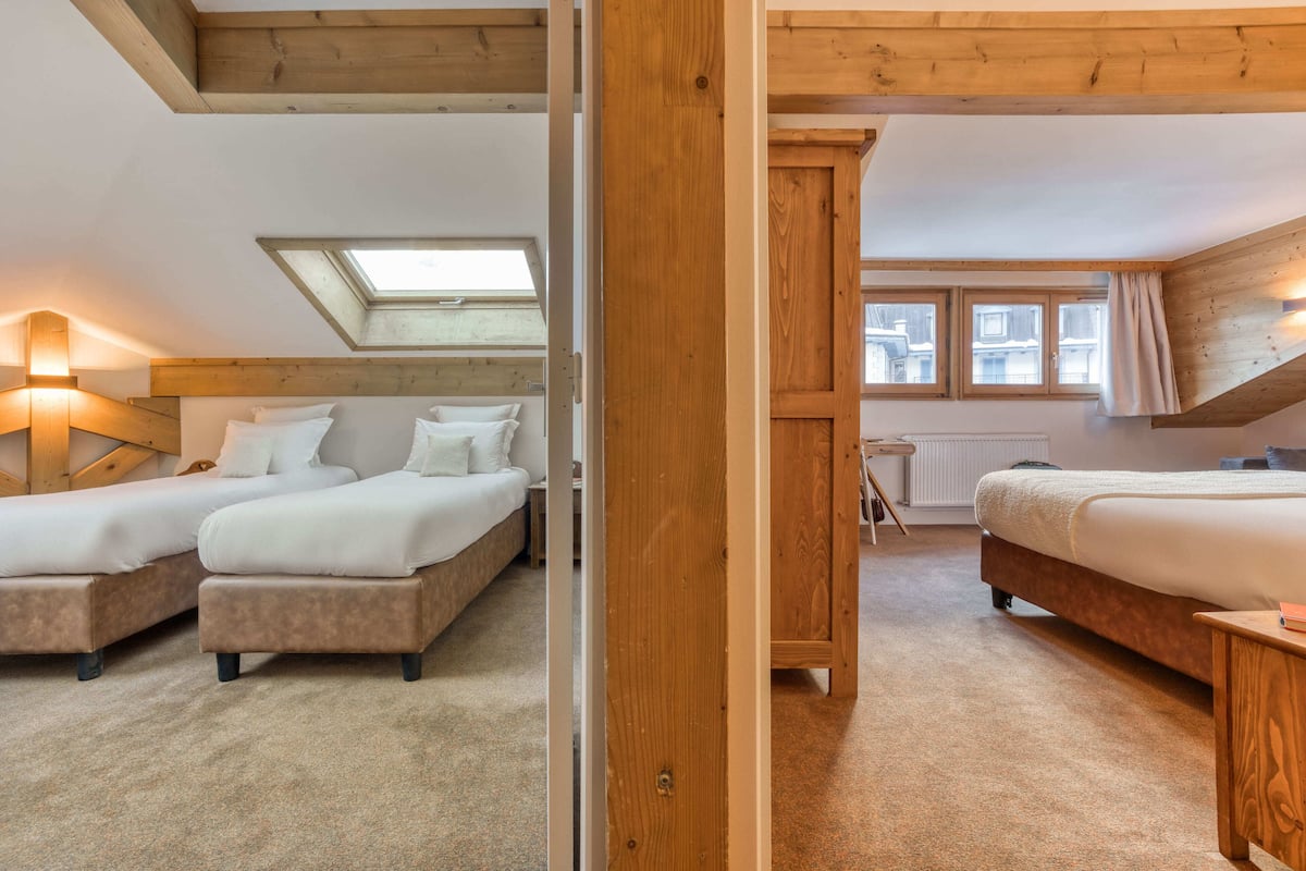 Une chambre avec deux lits, une fenêtre de toit et une vue sur l’extérieur.
