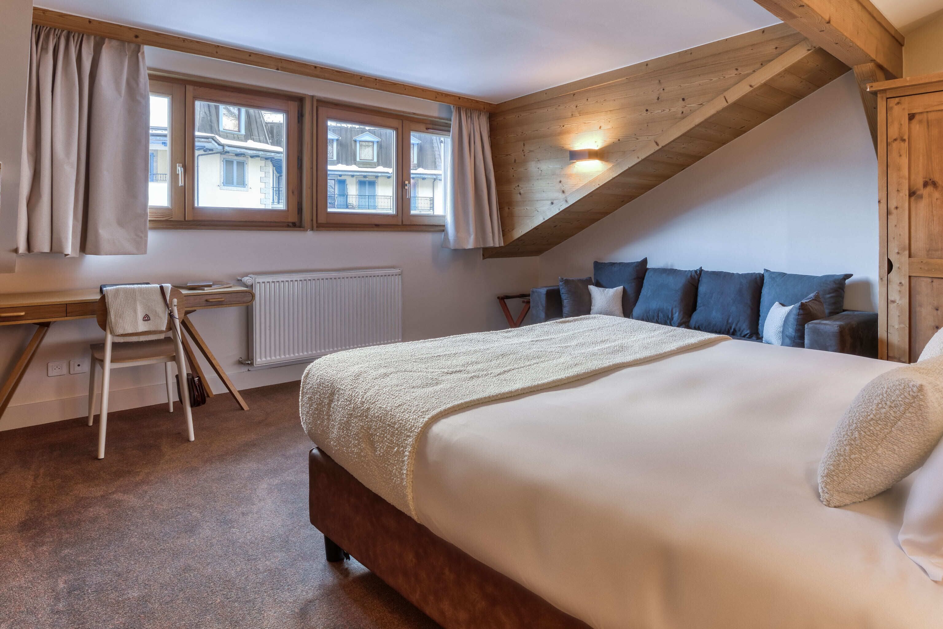 A bedroom with a bed, a desk, and a chair.