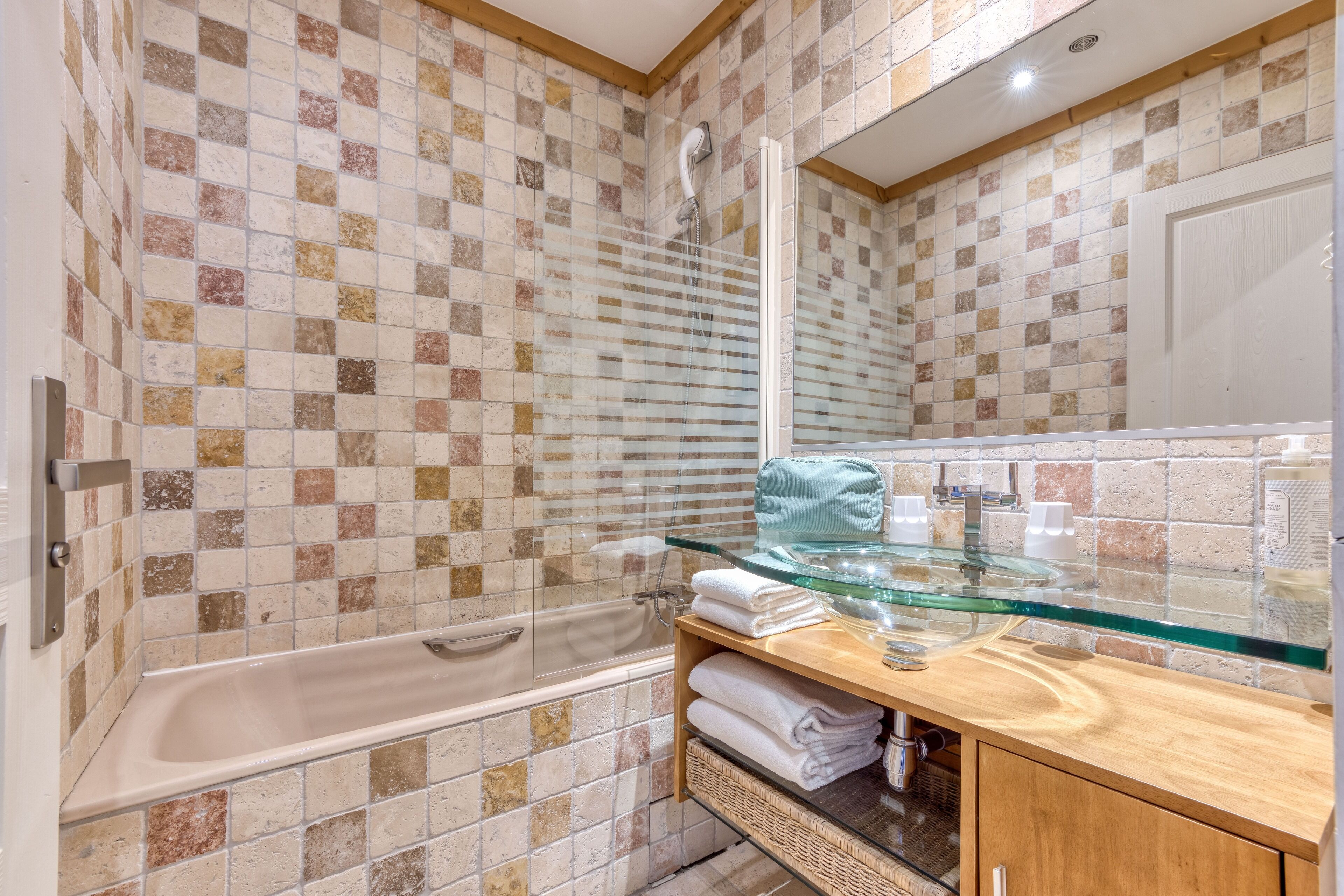 Un baño con bañera, cabina de ducha de vidrio y tocador con cubierta de cristal.