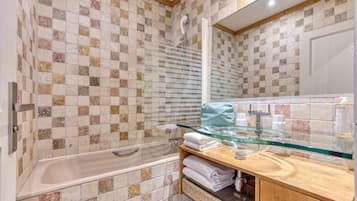 Un baño con bañera, cabina de ducha de vidrio y tocador con cubierta de cristal.