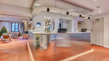 A modern reception area with a curved counter, a Christmas tree, and a stone wall in the background.